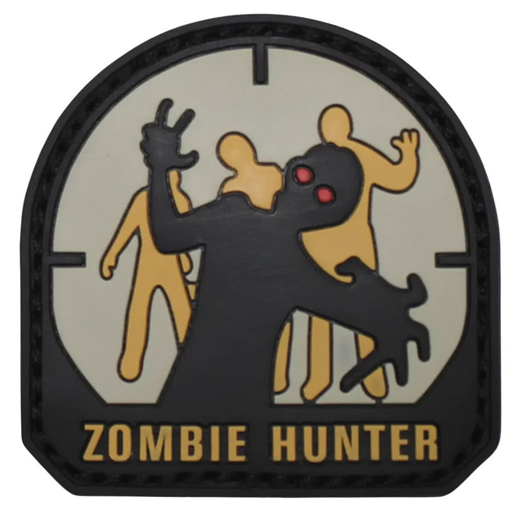 A circular tactical patch with a black border and the words 'ZOMBIE HUNTER' at the bottom. The design shows a black zombie figure in front of three tan figures on a light gray background, with red eyes.